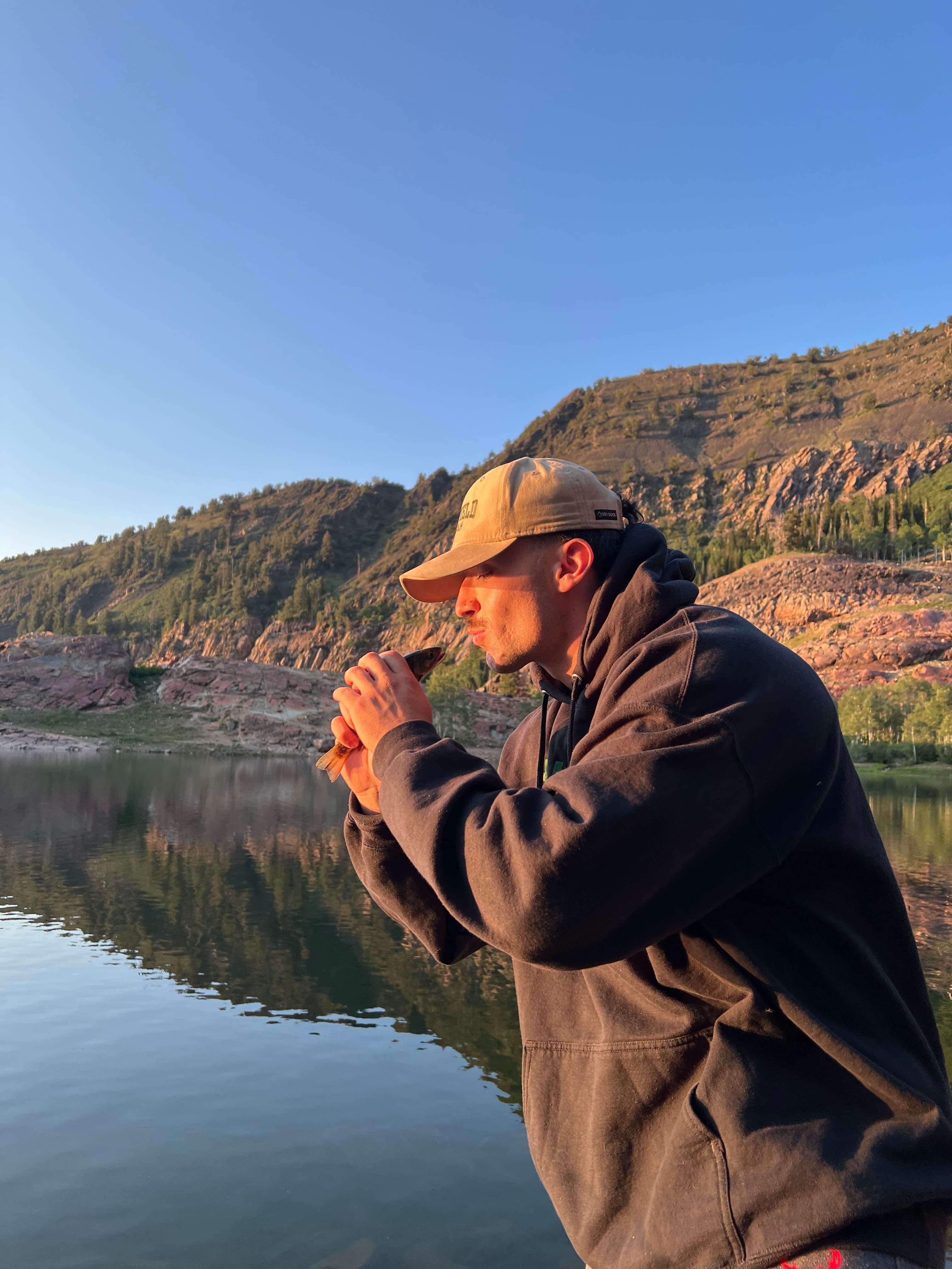 Coach Anthony kissing a fish on a fishing trip