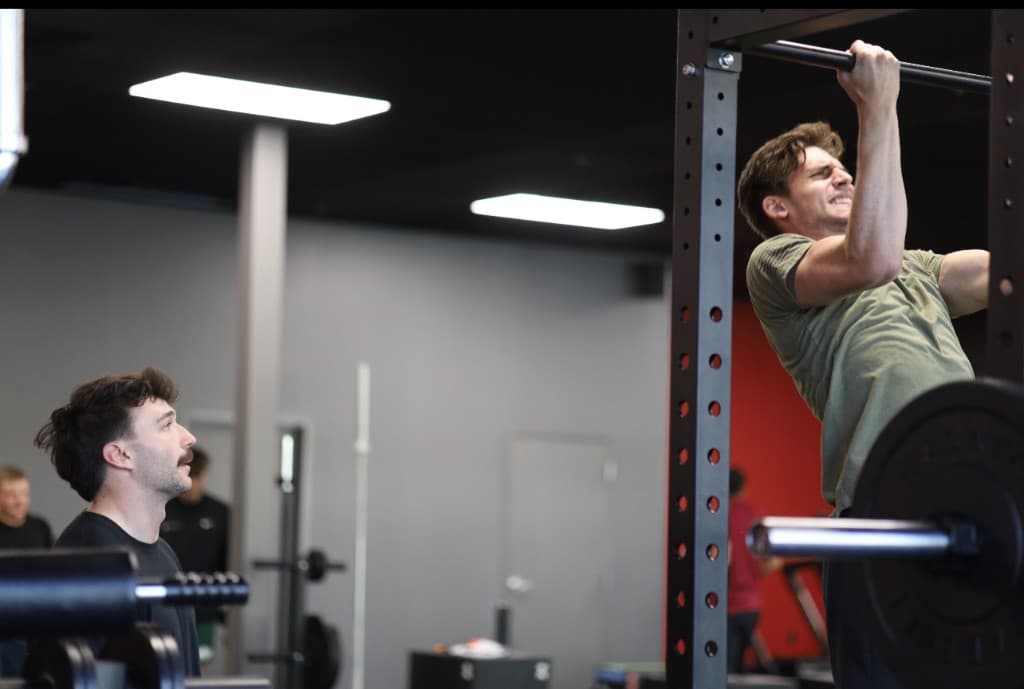 Trainer watching client do pull-ups